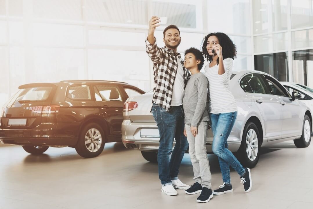 Mother, father and son are taking selfie in front of new grey car